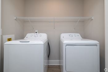 Two white front loading washing machines in a laundry room